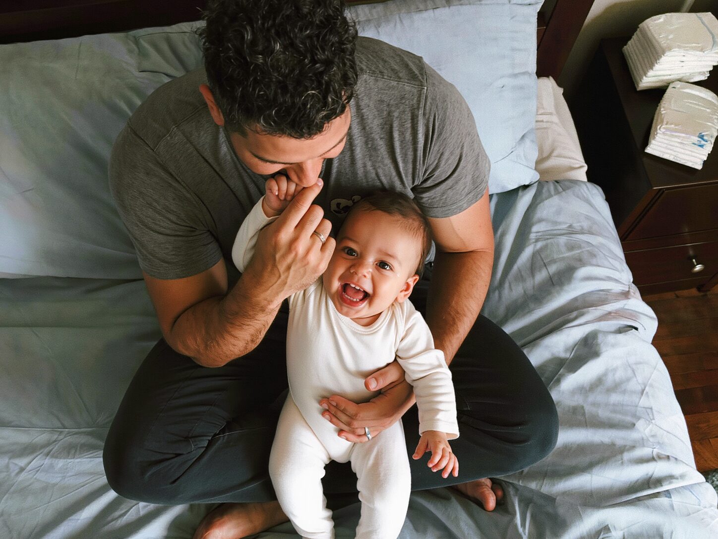 Papá jugando con su bebé sentado en la cama